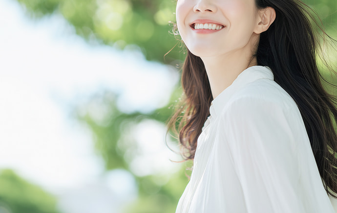 緑の木々のもとで笑顔を見せる女性