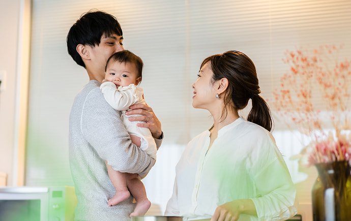 ソファで赤ちゃんを囲んで笑顔の夫婦