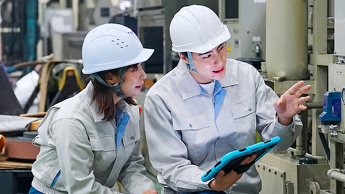 ヘルメット着用の2人が工場内でタブレットを囲んで確認している様子