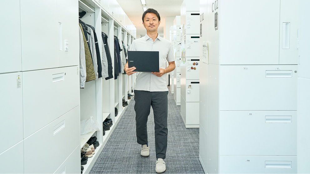 PCを持って正面を向くT.Y.さん