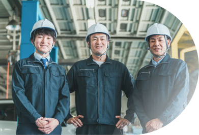 ヘルメットと作業服を着て工場内に並ぶ3人の男性